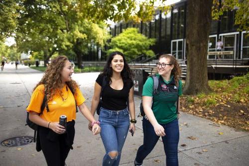Three students walk down the main stretch of campus