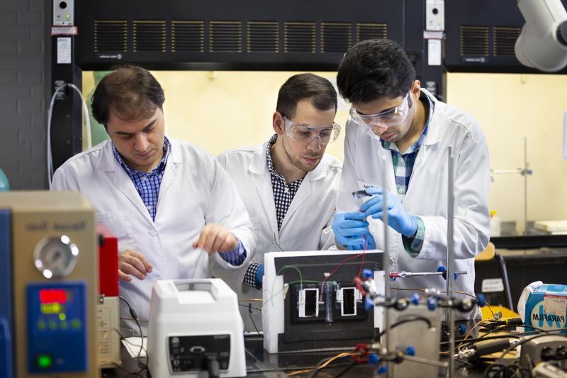 Graduate students work in an electrical engineering lab with their professor. 