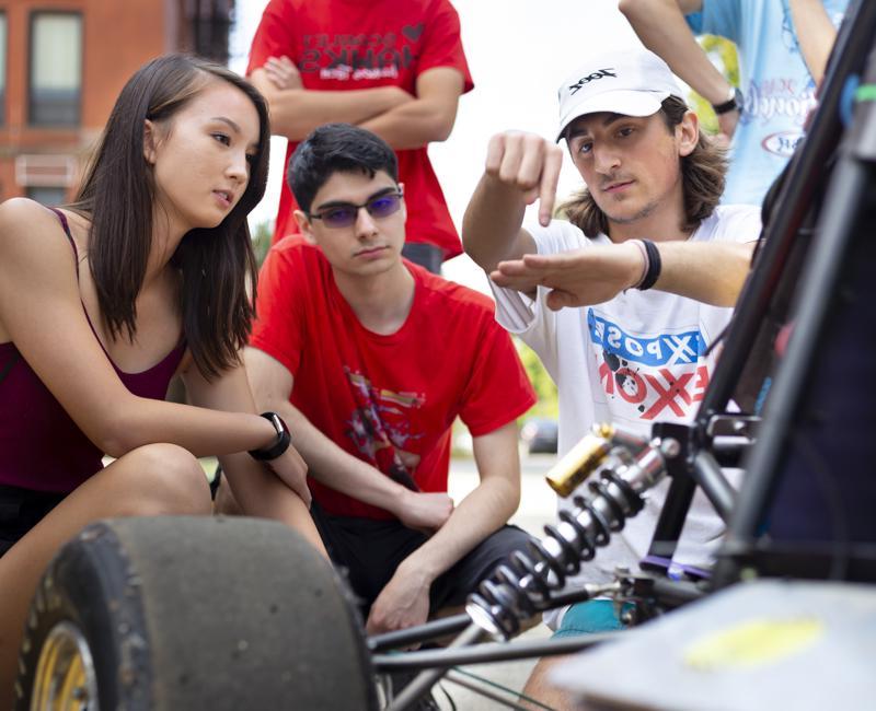 A member of the IIT motorsports club explains mechanics to two students